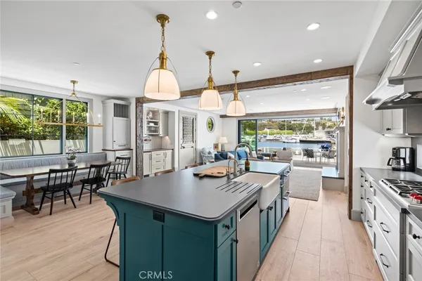 a kitchen with stainless steel appliances granite countertop a stove a refrigerator a dining table and chairs with wooden floor