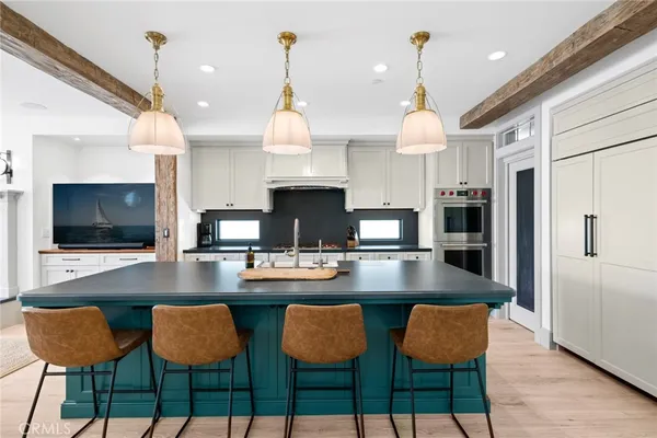 a kitchen with stainless steel appliances kitchen island granite countertop a dining table chairs and a refrigerator