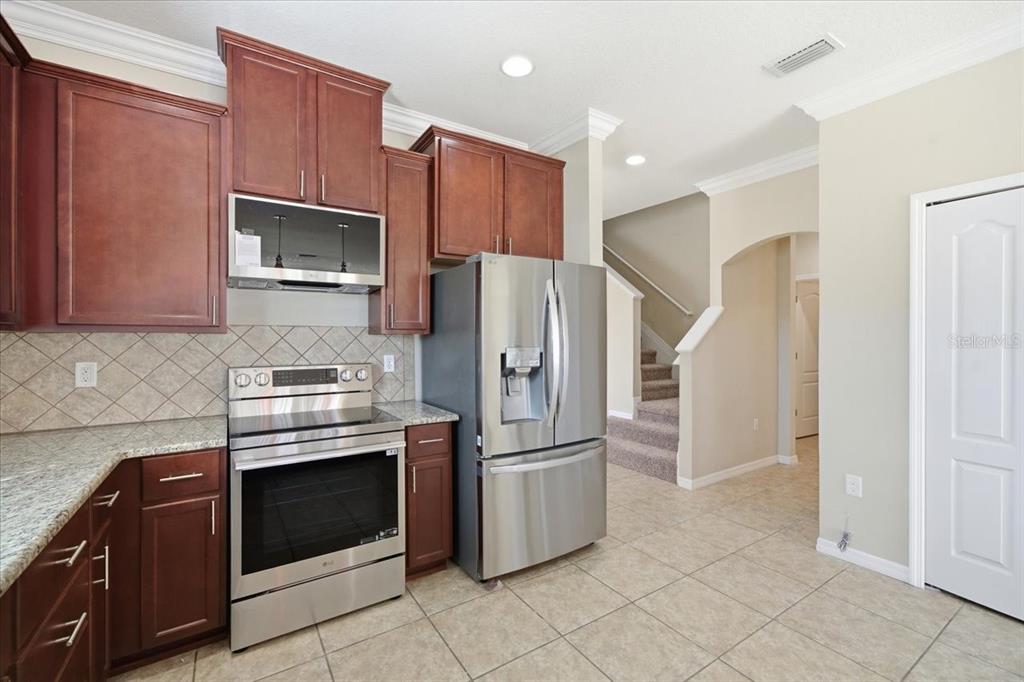 13366 Barkingside Place Spring Hill, FL 34609 - Photo 14 of 41 a kitchen with stainless steel appliances granite countertop a refrigerator and a stove top oven