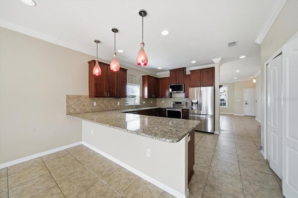 13366 Barkingside Place Spring Hill, FL 34609 - Photo 16 of 41 a kitchen with stainless steel appliances granite countertop a sink a stove and a refrigerator