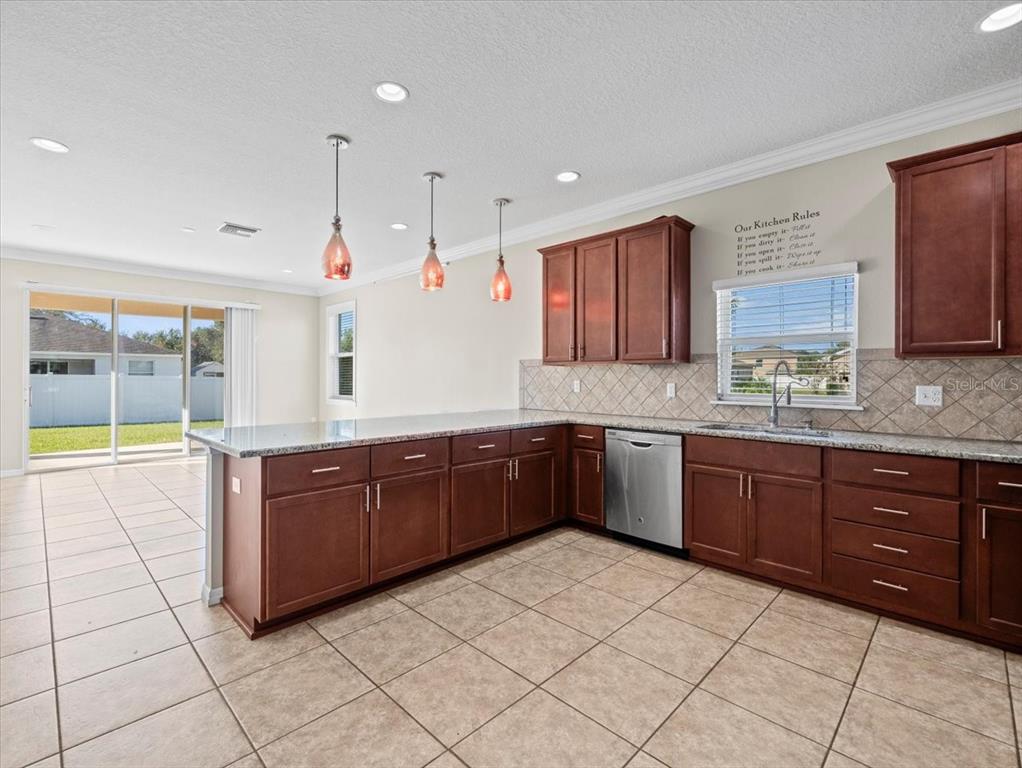13366 Barkingside Place Spring Hill, FL 34609 - Photo 17 of 41 a large kitchen with stainless steel appliances granite countertop a stove a sink and a microwave