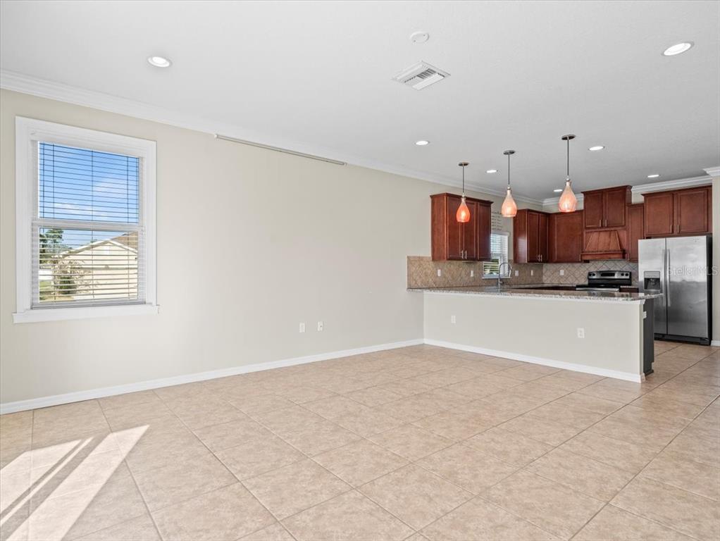 13366 Barkingside Place Spring Hill, FL 34609 - Photo 19 of 41 a large kitchen with stainless steel appliances kitchen island granite countertop a refrigerator a stove a sink and a white cabinets