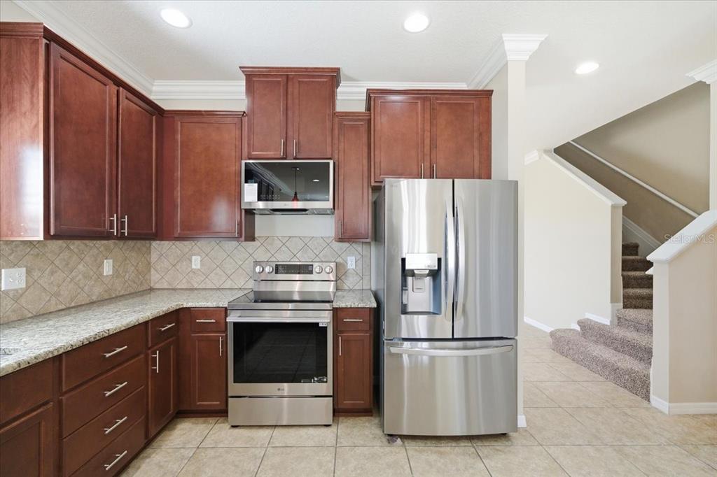 13366 Barkingside Place Spring Hill, FL 34609 - Photo 10 of 41 a kitchen with stainless steel appliances granite countertop a refrigerator stove a sink and dishwasher