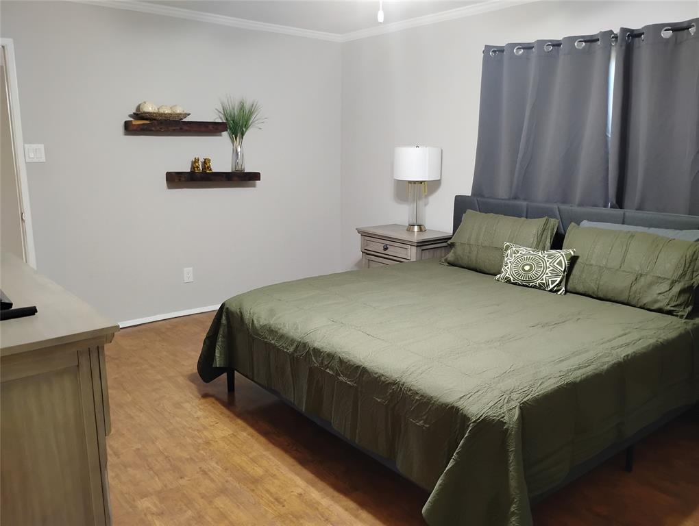1954 Rambling Ridge Lane Carrollton, TX 75007 - Photo 13 of 20 Light-toned wood-finish flooring provides a warm base for this room, featuring light gray walls with white crown molding and baseboards