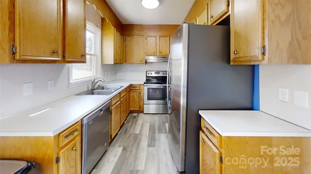 a kitchen with stainless steel appliances granite countertop a sink a stove and a refrigerator