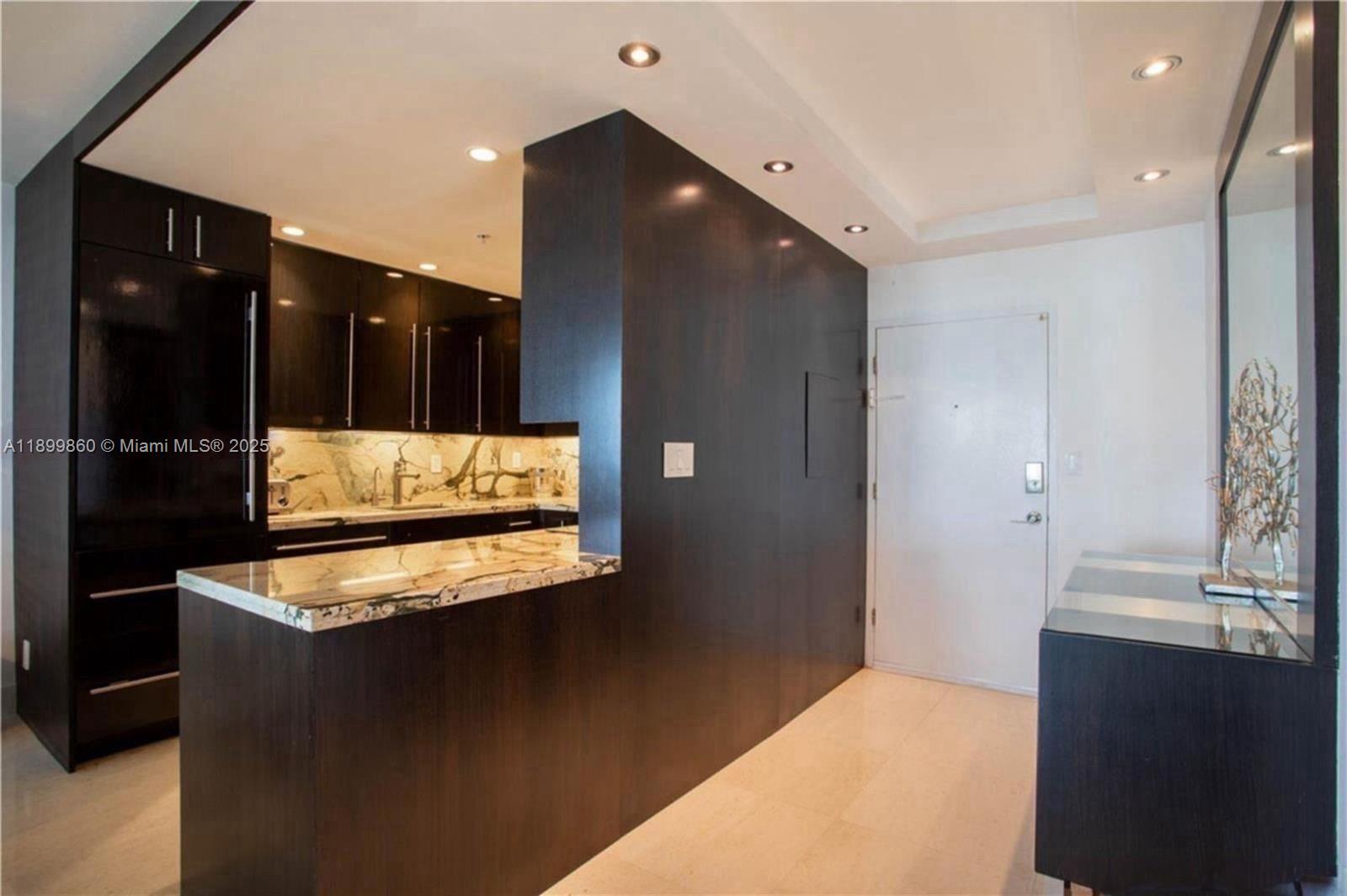 100 Lincoln Road, Unit 647 Miami Beach, FL 33139 - Photo 8 of 10 a kitchen with granite countertop white cabinets and black appliances