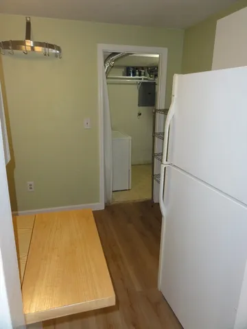 a view of a room with wooden floor and a refrigerator
