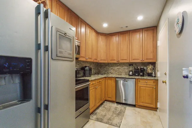 a kitchen with stainless steel appliances granite countertop a refrigerator and a sink