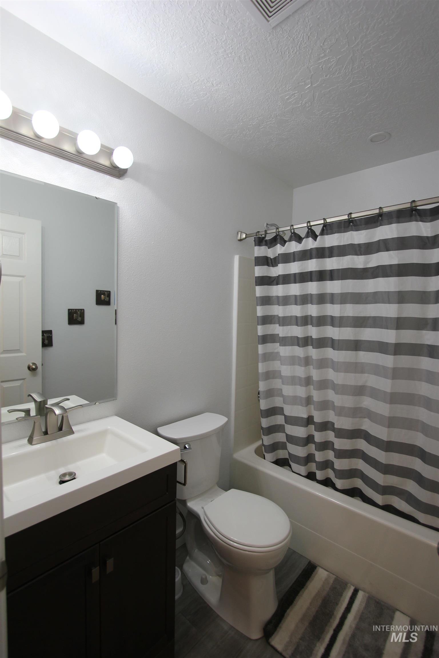 4816 Kadie Street Caldwell, ID 83607 - Photo 17 of 23 Full bathroom featuring a white porcelain toilet, a tub with a shower fixture, and a vanity with a white countertop and dark wood-finish cabinetry