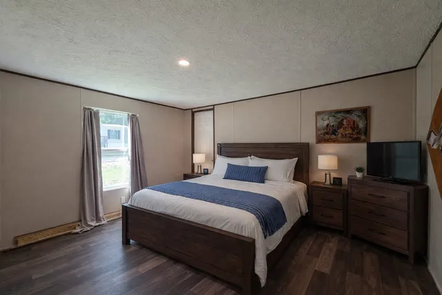 a bedroom with a bed and a flat tv screen on a dresser