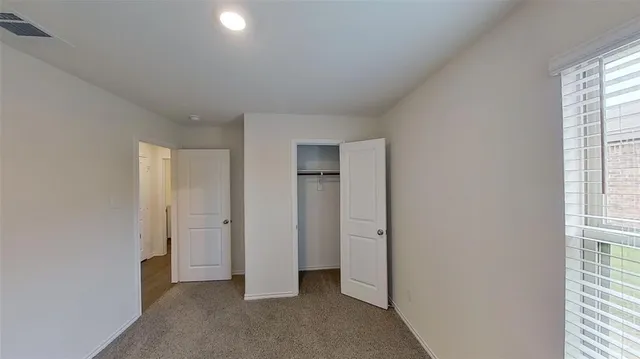 an empty room with closet and windows