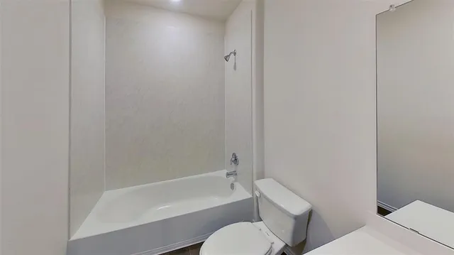 a white toilet sitting next to a bath tub