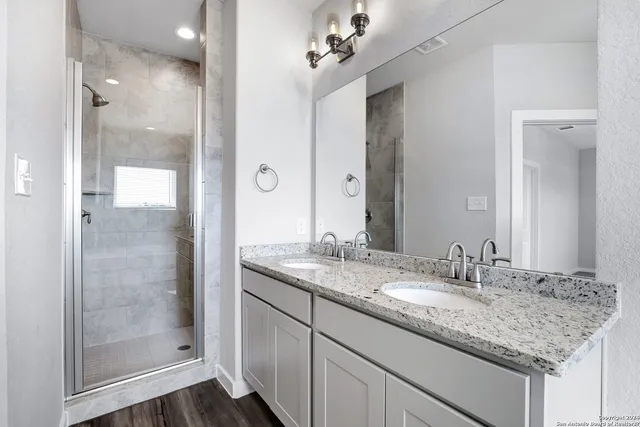 a bathroom with a granite countertop sink a mirror and a shower