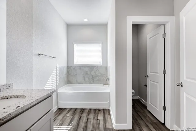 a bathroom with a granite countertop bathtub shower sink and toilet