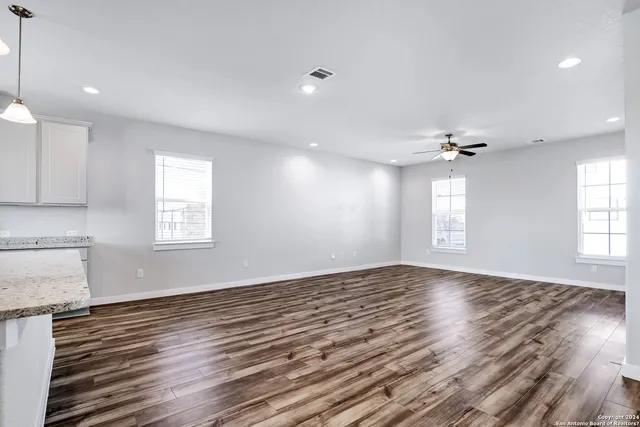 a view of empty room with wooden floor and fan
