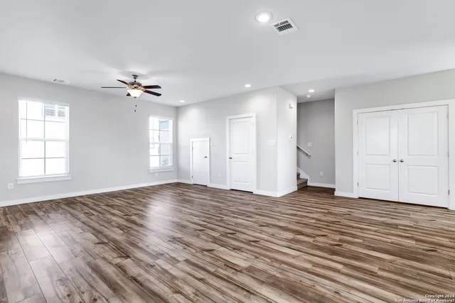 a view of an empty room with a window and wooden floor