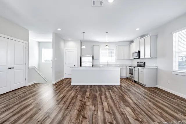 a large kitchen with kitchen island white cabinets and stainless steel appliances