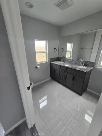 a bathroom with a granite countertop sink a toilet and mirror