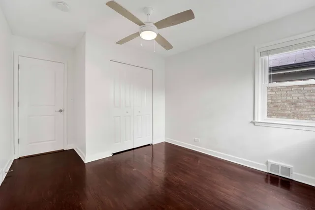 an empty room with wooden floor chandelier fan and windows
