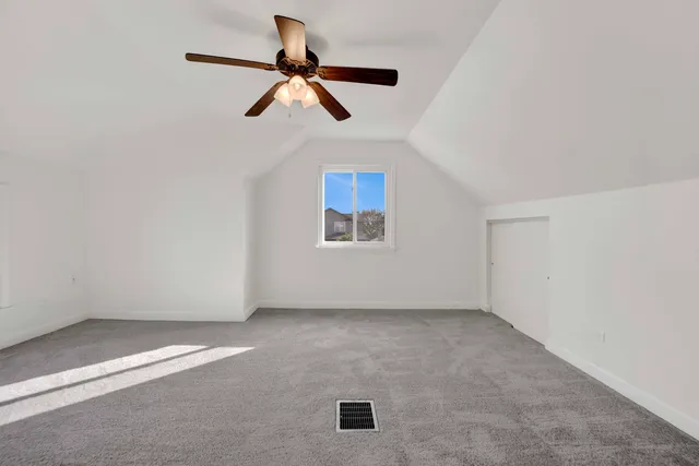 an empty room with ceiling fan and windows