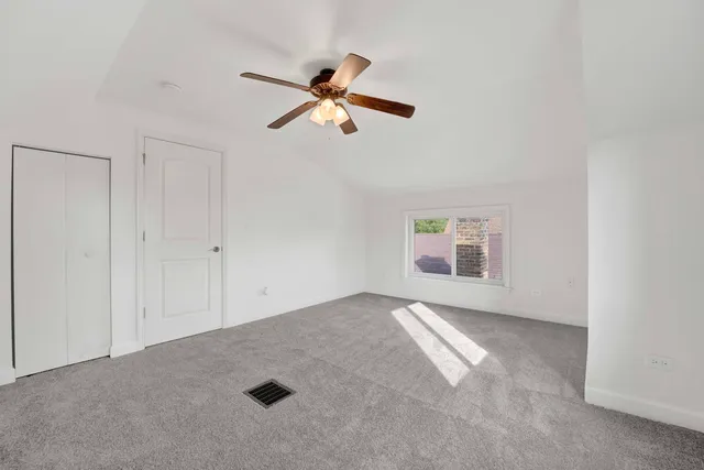 an empty room with windows and fan