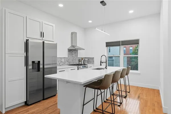 a kitchen with stainless steel appliances a dining table chairs and wooden floor