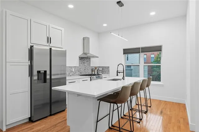 a kitchen with stainless steel appliances a dining table chairs and wooden floor