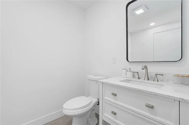 a bathroom with a granite countertop toilet sink mirror and vanity