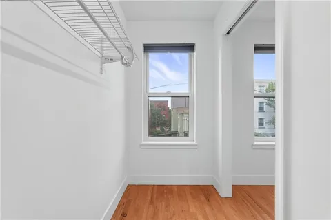a view of an empty room with wooden floor and a window