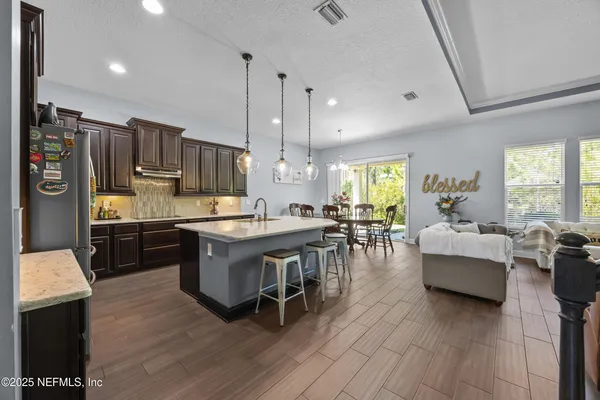 a kitchen with stainless steel appliances granite countertop a table chairs stove and refrigerator