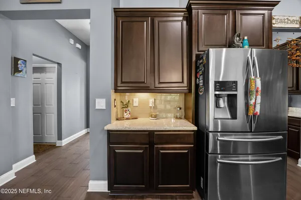 a kitchen with stainless steel appliances kitchen island granite countertop a stove a refrigerator a sink a dining table and chairs with wooden floor
