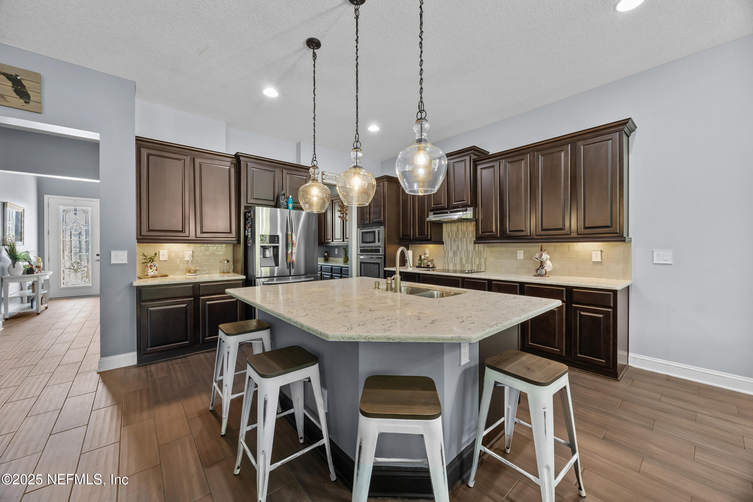 45 Oban Court St. Johns, FL 32259 - Photo 17 of 53 a kitchen with stainless steel appliances kitchen island granite countertop a stove a refrigerator a sink a dining table and chairs with wooden floor