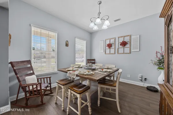 a view of a dining room with furniture a chandelier and wooden floor
