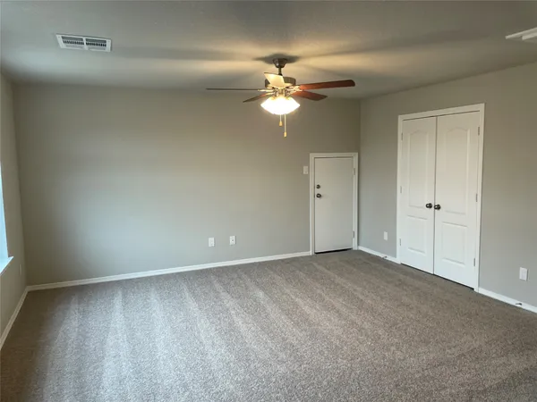 a view of an empty room and chandelier fan