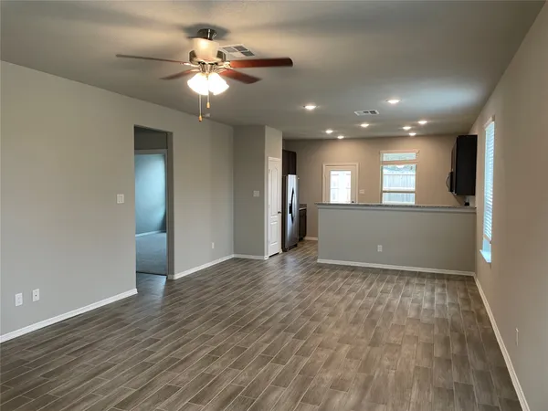 a view of an empty room and a kitchen
