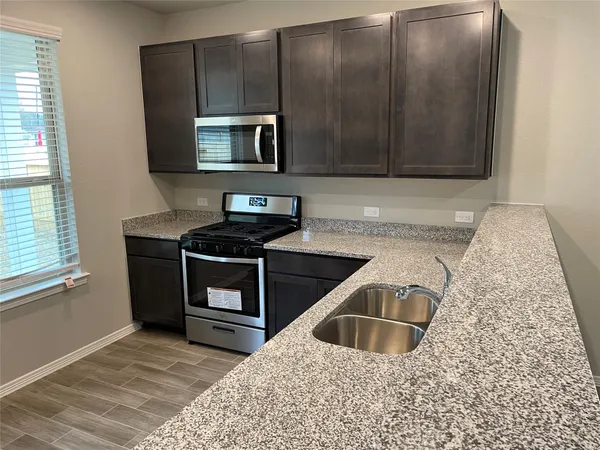 a kitchen with granite countertop a sink a stove and microwave