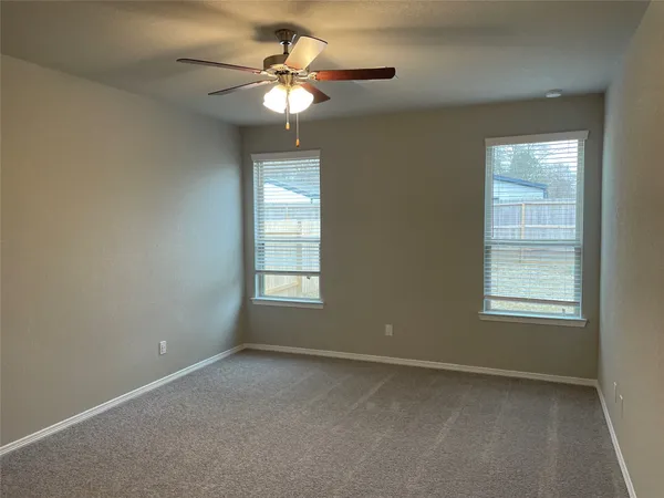 an empty room with windows and fan
