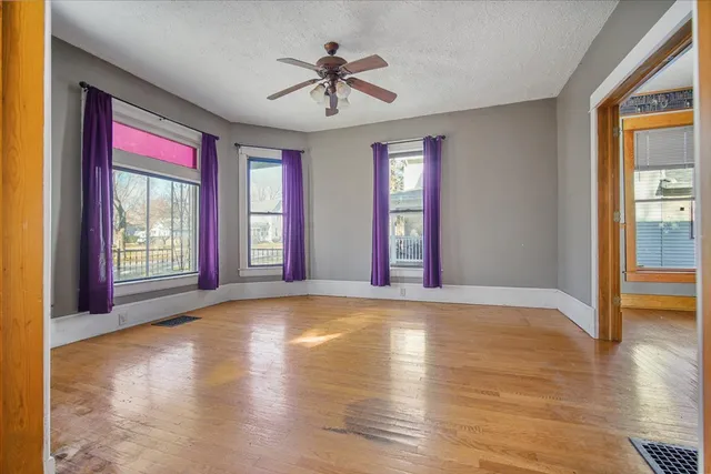 a view of an empty room with a window and wooden floor