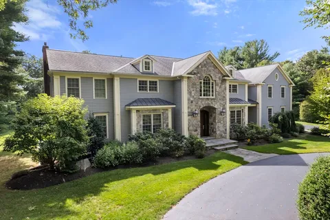 a front view of a house with garden and trees
