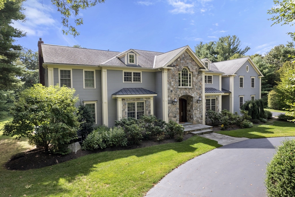 a front view of a house with garden and trees