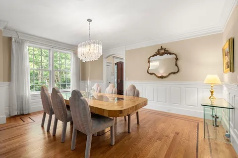 a dining room with wooden floor a chandelier a wooden table and chairs