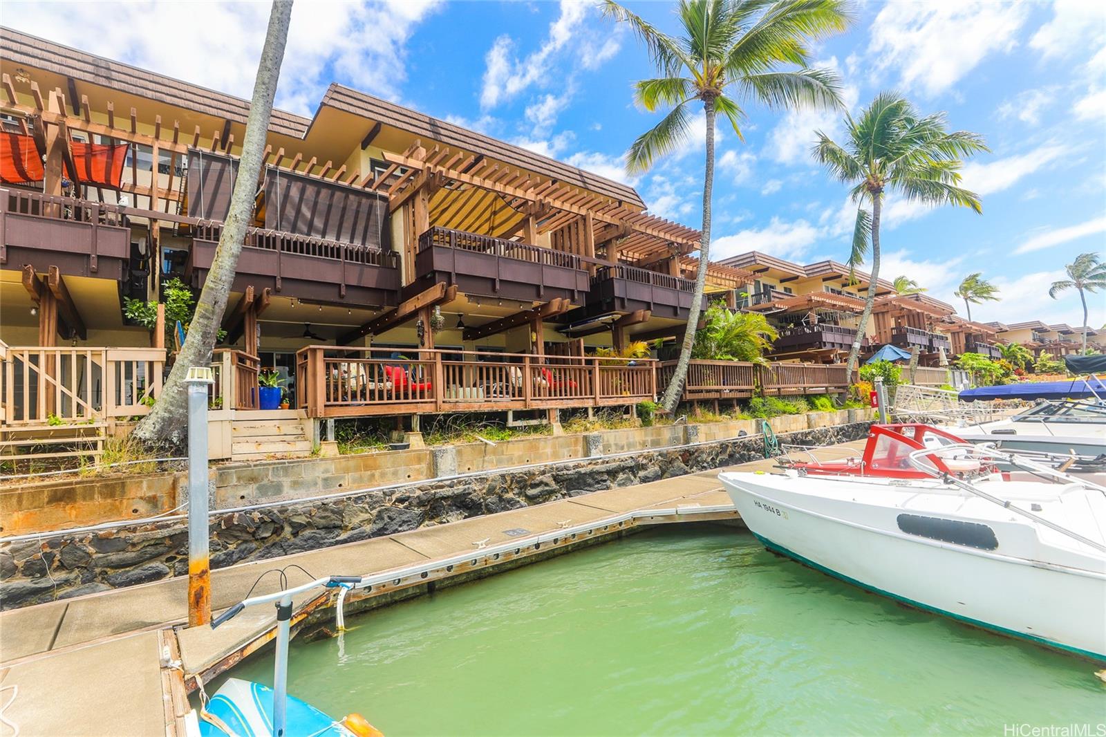 444 Lunalilo Home Road, Unit 312 Honolulu, HI 96825 - Photo 6 of 25 a blue swimming pool with a lawn chairs under an umbrella