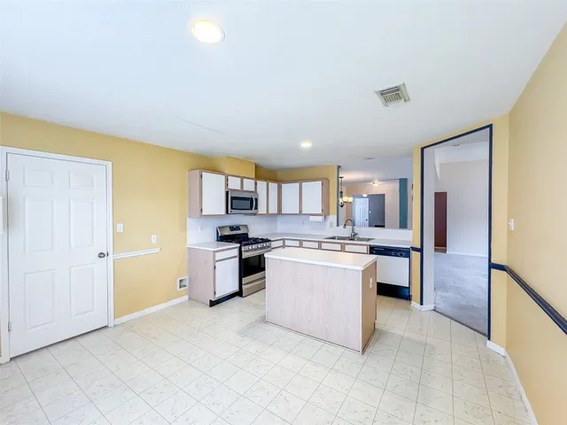 a large kitchen with a stove a refrigerator a sink dishwasher with a dining table and chairs