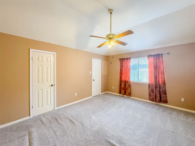 a view of an empty room with window and chandelier fan