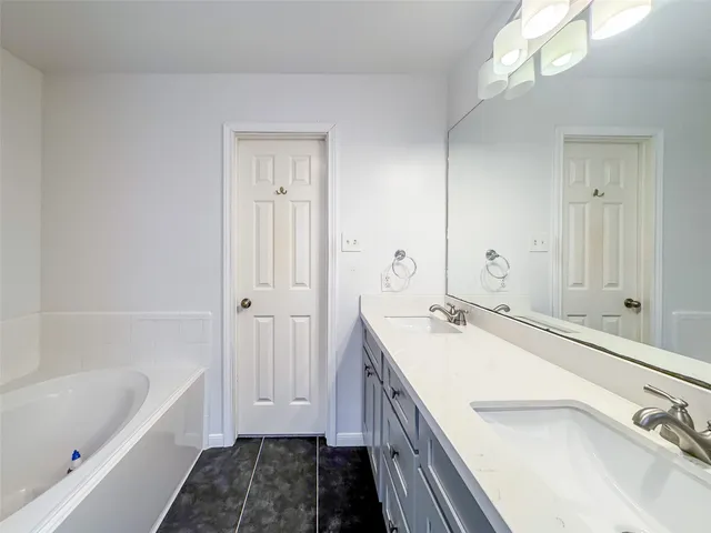 a bathroom with a tub sink and mirror