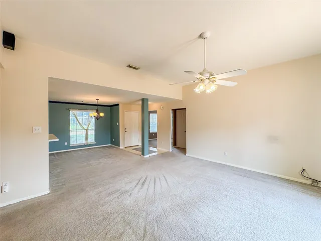 an empty room with chandelier and windows