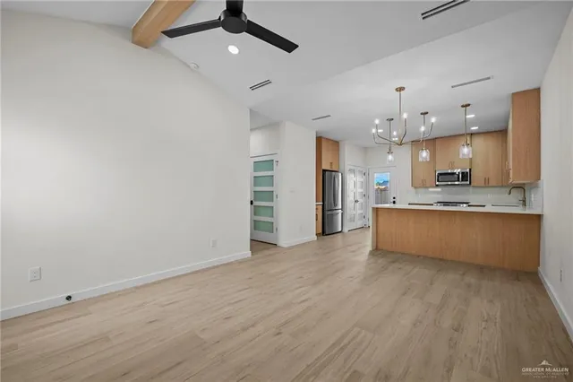 a large kitchen with a wooden floor and stainless steel appliances