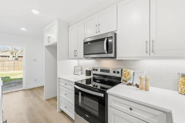 a kitchen with stainless steel appliances granite countertop white cabinets and a stove top oven