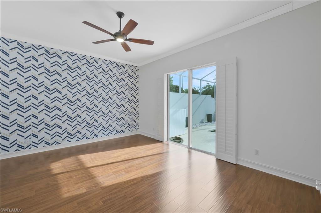6044 Andros Way Naples, FL 34119 - Photo 20 of 46 Unfurnished room featuring baseboards, wood finished floors, ornamental molding, and an accent wall