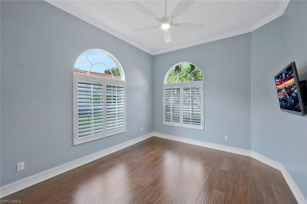 6044 Andros Way Naples, FL 34119 - Photo 23 of 46 Empty room featuring baseboards, ornamental molding, a ceiling fan, and dark wood finished floors